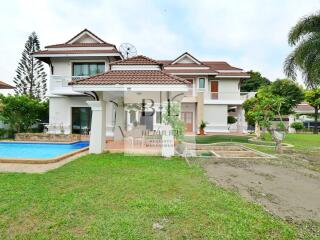 Exterior view of a large house with a yard and pool