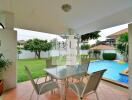 Outdoor patio area with table and chairs next to a swimming pool