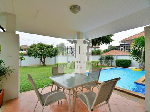 Outdoor patio area with table and chairs next to a swimming pool