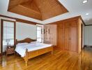 Spacious bedroom with wooden furniture and unique ceiling design