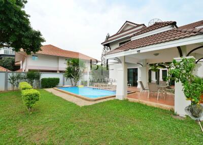 Exterior view of a residential house with a swimming pool and patio area