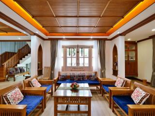 Spacious living room with wooden furniture and ceiling, featuring ample seating and natural light.