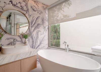 Modern bathroom with floral wallpaper, round mirror, and a freestanding bathtub