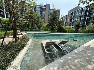 Outdoor swimming pool with lounge chairs and surrounding greenery in a residential complex