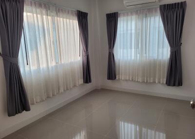 Empty bedroom with tiled floor and large windows with curtains