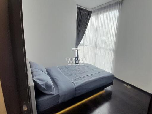 Modern bedroom with a large window, dark flooring, and blue bedding