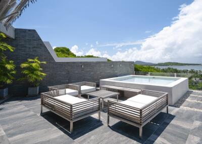 Modern outdoor patio with seating area and hot tub overlooking scenic view