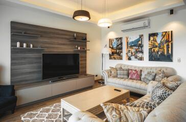 Modern living room with cozy sofas, wall-mounted TV, and artwork