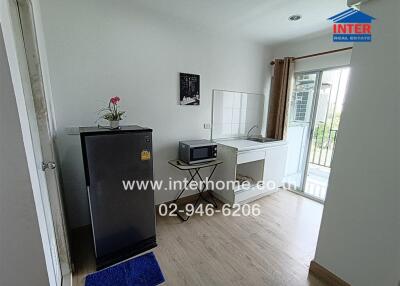 Small kitchen with mini-fridge and microwave, leading to balcony view