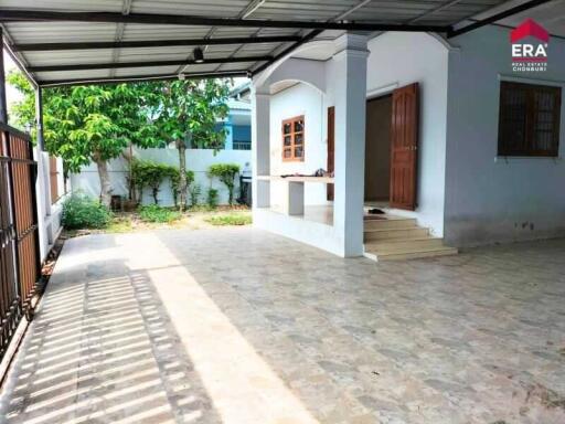 Outdoor partly covered area with tiled flooring and a small porch with steps leading to a wooden door