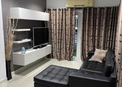 Modern living room with black leather sectional sofa and wall-mounted TV