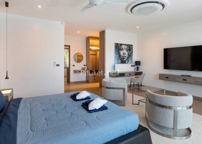 Modern bedroom with blue bedding, modern furnishings, and a large television