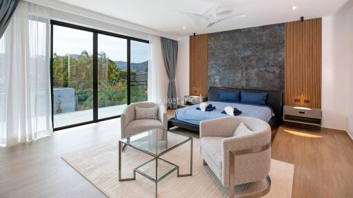 Spacious bedroom with a glass wall, modern furniture, and a scenic view