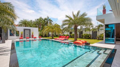 Luxury outdoor swimming pool area with sun loungers and palm trees