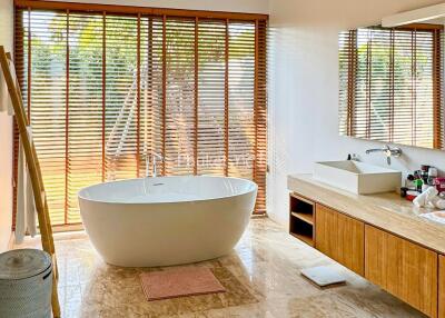 Spacious bathroom with large bathtub and wooden blinds