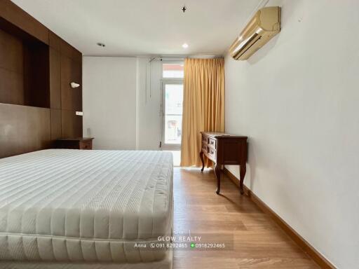 Spacious bedroom with bed, wooden flooring, and air conditioning