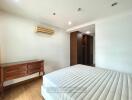 Spacious bedroom with wooden dresser and built-in closet