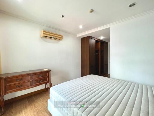 Spacious bedroom with wooden dresser and built-in closet