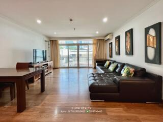 Modern living room with large glass doors, black leather sofa, and wooden furniture