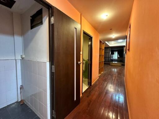 Illuminated hallway with wooden flooring and orange walls