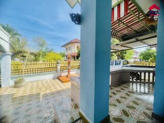 Covered outdoor space with tiled flooring and nearby greenery