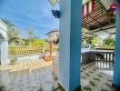 Covered outdoor space with tiled flooring and nearby greenery