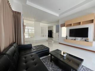 Modern living room with black leather sofa and wall-mounted TV