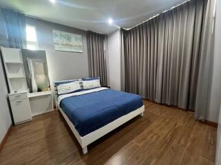 Spacious bedroom with a large bed, wooden flooring, and ample natural light.