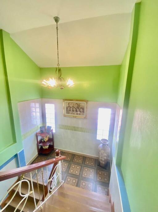 Bright staircase with green walls and chandelier