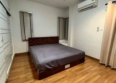 Spacious bedroom with wooden flooring and air conditioning