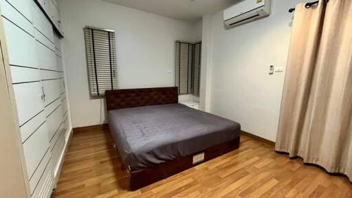 Spacious bedroom with wooden flooring and air conditioning