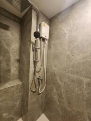 A modern shower area with a wall-mounted water heater and gray stone tile walls