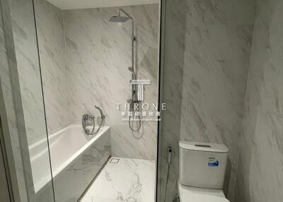 Modern bathroom with marble tiles, glass-enclosed shower, and toilet