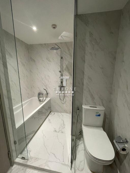 Modern bathroom with marble tiles, glass-enclosed shower, and toilet