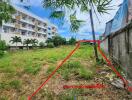 Vacant land plot adjacent to a multi-story building with trees