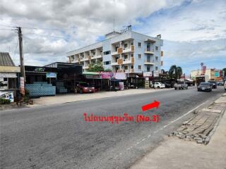 Street view showing buildings, shops, and road with vehicles