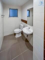 modern white-tiled bathroom with toilet and sink