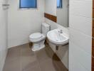 modern white-tiled bathroom with toilet and sink