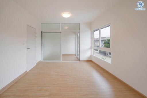 Spacious empty bedroom with wooden flooring and large windows