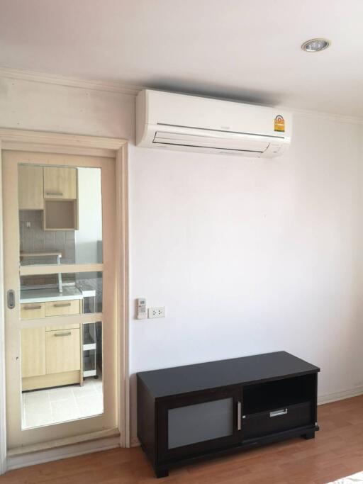 Living space with air conditioner and cabinet, view of the kitchen through glass door