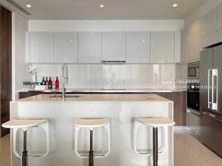 Modern kitchen with an island, bar stools, and stainless steel appliances.