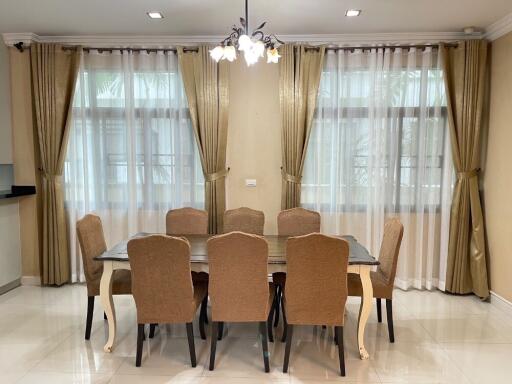 Spacious dining room with elegant chandelier, large dining table, and windows with curtains