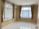 Empty bedroom with tiled floor and large windows with curtains