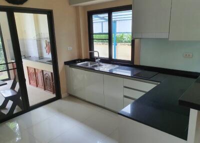 Modern kitchen with black countertops and white cabinets featuring a view of the patio