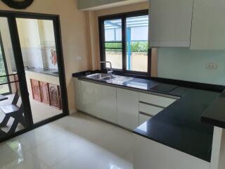 Modern kitchen with black countertops and white cabinets featuring a view of the patio