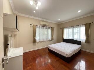 Spacious bedroom with wooden flooring, large windows, and a comfortable bed