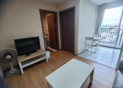 Living room with television, table, and view to balcony