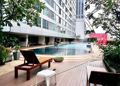 Outdoor swimming pool area with sun loungers and surrounding greenery