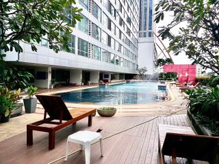 Outdoor swimming pool area with sun loungers and surrounding greenery