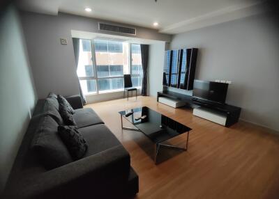 modern living room with large window, sofa, TV, and coffee table